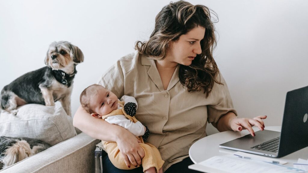 mother cradling her baby while working from home